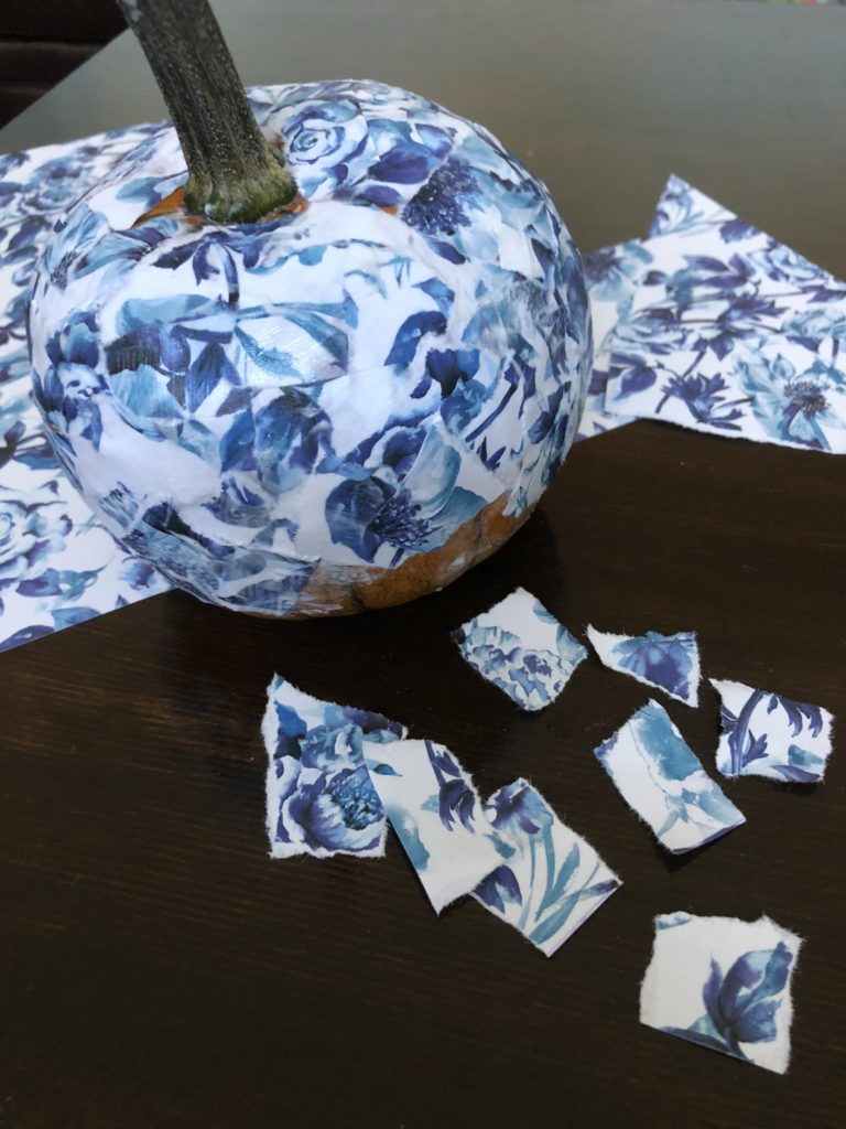 Learn how to make a DIY decoupage blue and white floral pumpkin with Modge Podge and scrapbook paper.